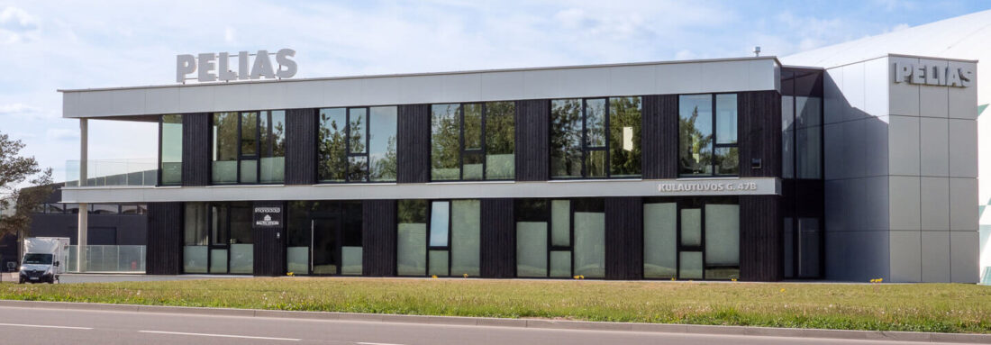 Close up of full street view of the Pelias office building in Kaunas, showcasing the rhythm of vertical Degmeda Deep Char Spruce cladding against modern glass and metal elements.