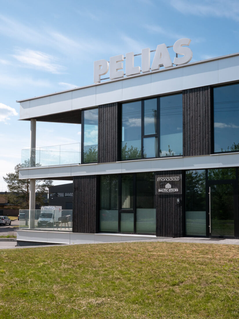 Front facade of the Pelias office building in Kaunas, featuring vertical Degmeda Deep Char Spruce cladding around the main entrance and glass balconies, with corporate signage clearly visible.